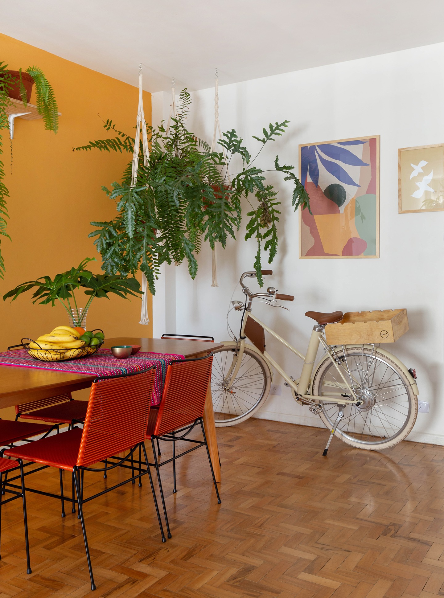 decoração obrah sala jantar parede mostarda quadros coloridos bicicleta e muitas plantas