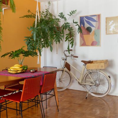 decoração obrah sala jantar parede mostarda quadros coloridos bicicleta e muitas plantas