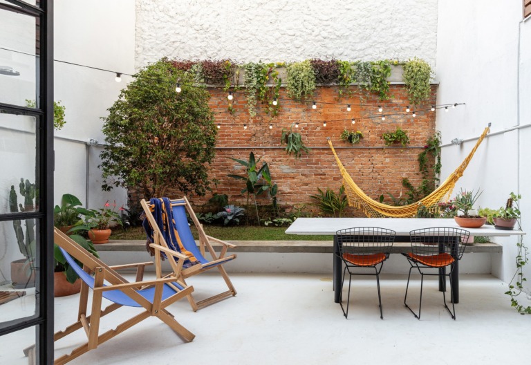 decoração quintal poltronas azuis rede amarela parede tijolos