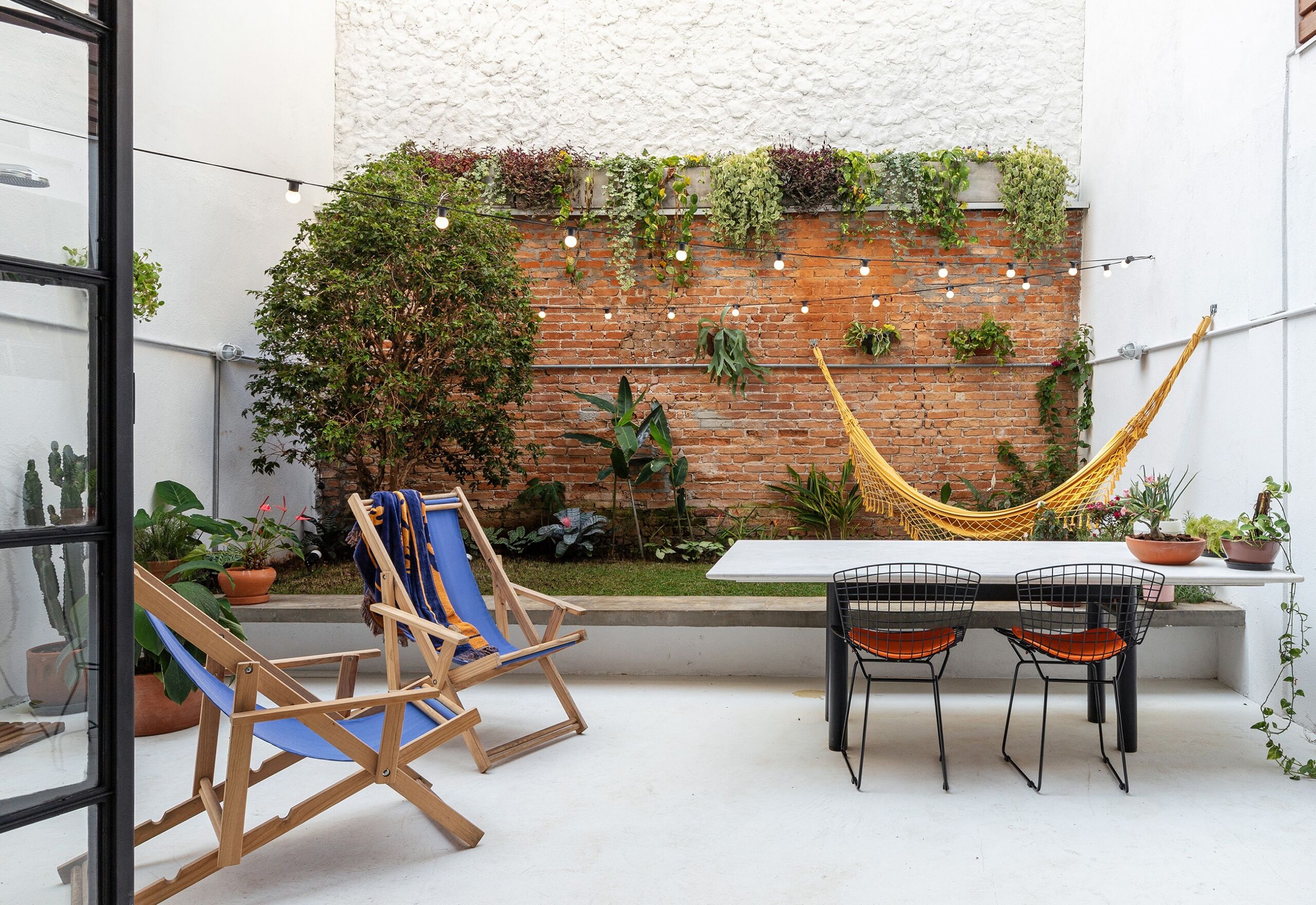 decoração quintal poltronas azuis rede amarela parede tijolos