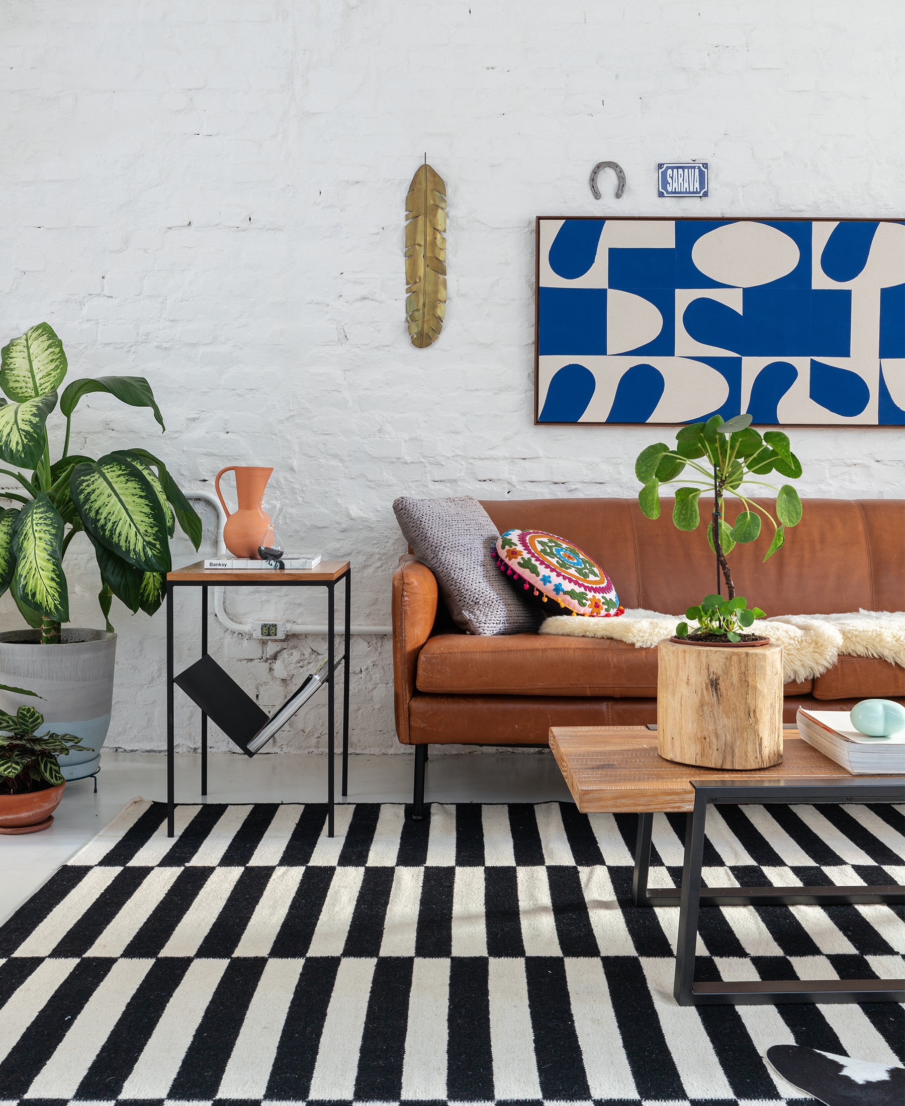 decoração sala parede tijolos brancos sofá couro marrom tapete listrado