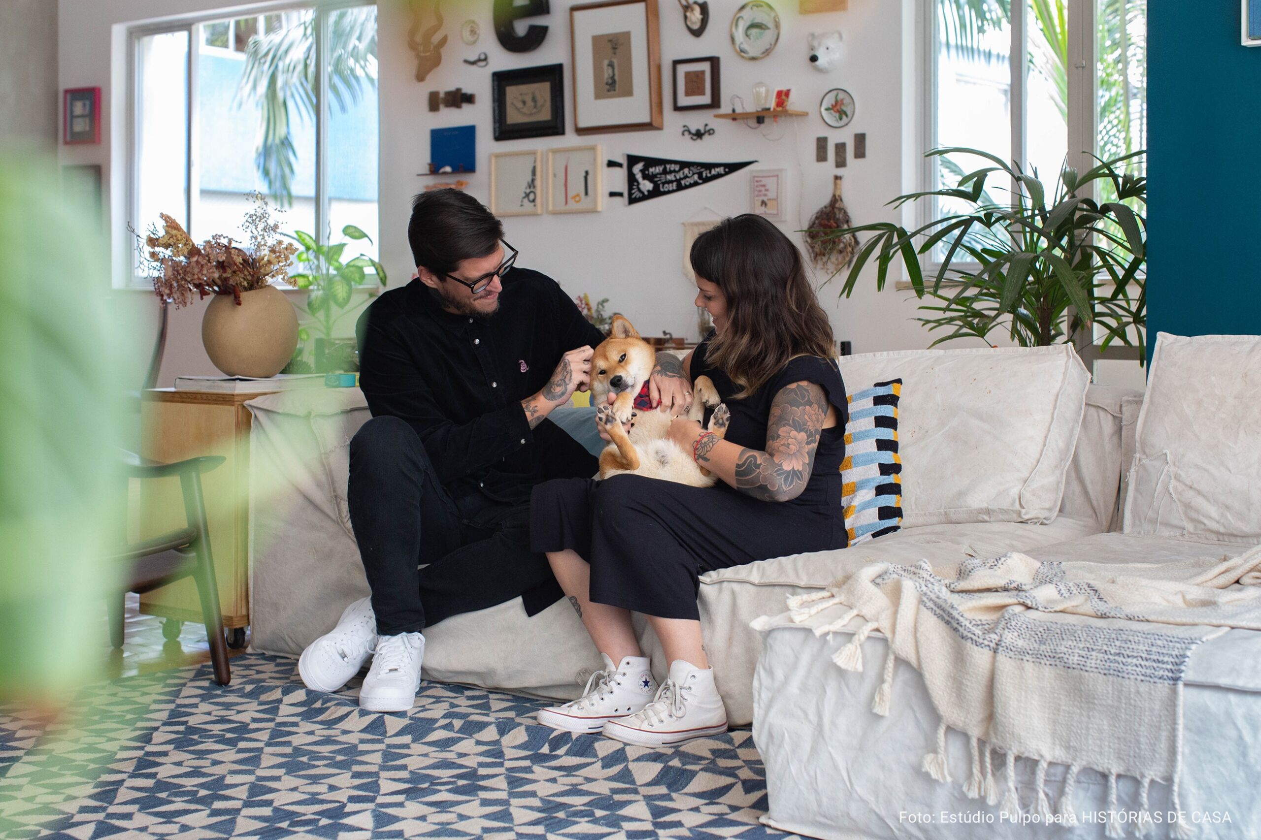 casal brincando com cachorro sentado no sofá