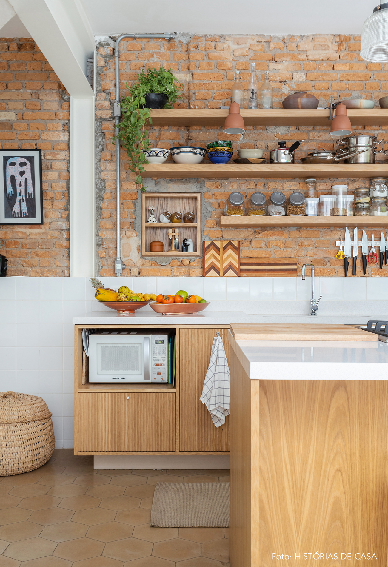 Cozinha com parede de tijolinho e marcenaria de madeira clara
