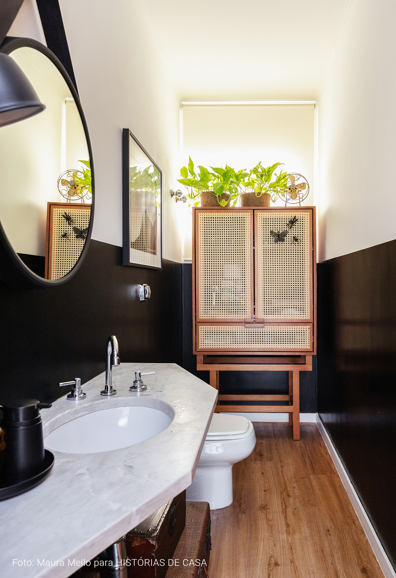 Lavabo com parede preta e armário de palhinha