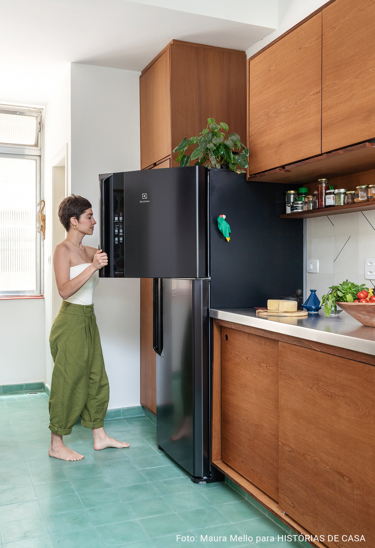 Cozinha integrada com piso verde e geladeira preta