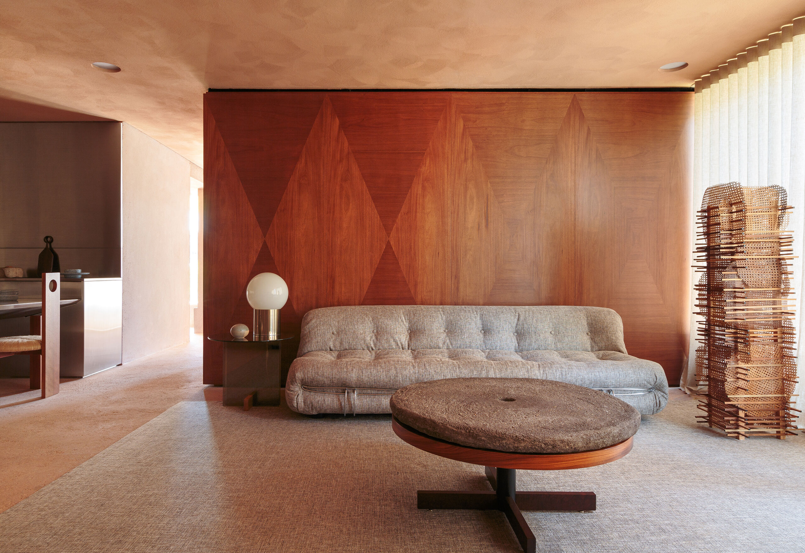 Apartamento em tons terrosos com janelas amplas e cozinha em inox.