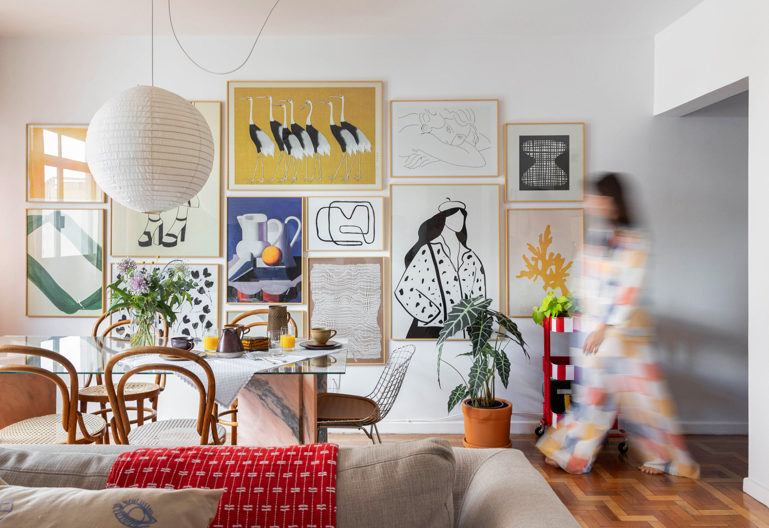 Apartamento com parede de quadros da Boemi, piso de tacos e decoração com móveis garimpados.