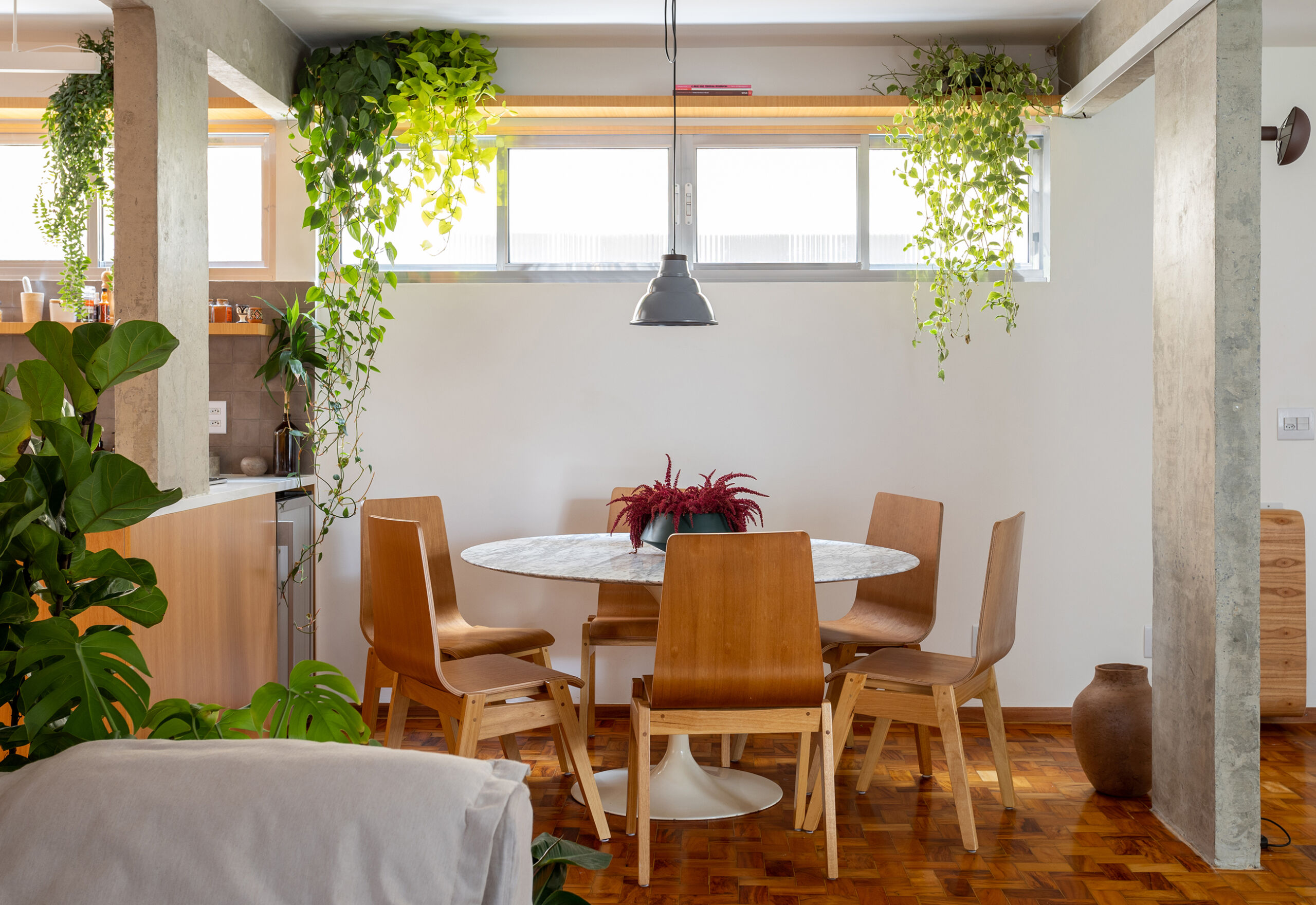 Apartamento com concreto, madeira e cozinha integrada.