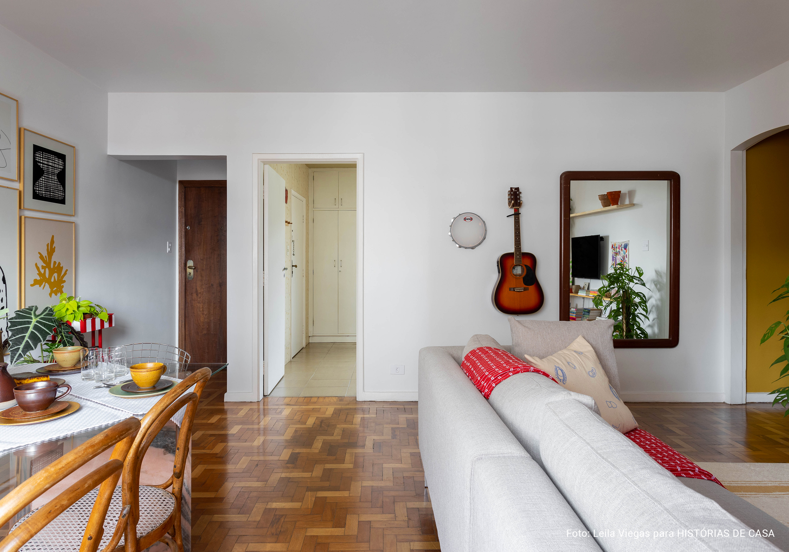 Apartamento com parede de quadros da Boemi, piso de tacos e decoração com móveis garimpados.