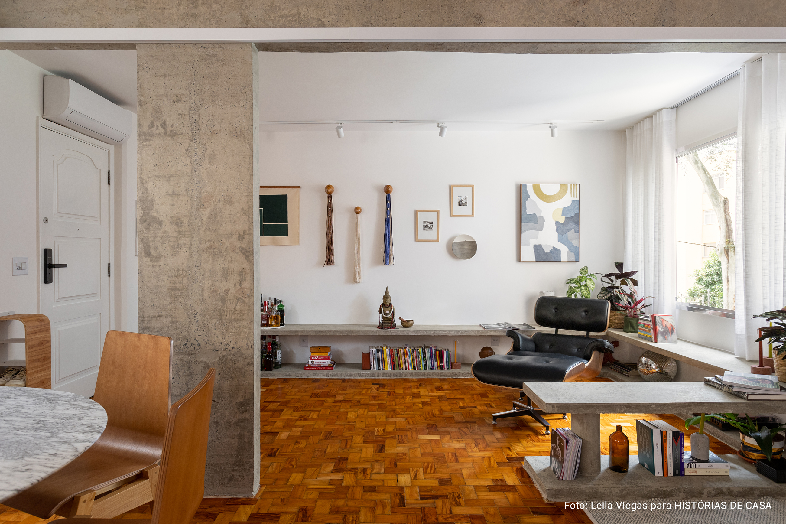 Apartamento com concreto, madeira e cozinha integrada.