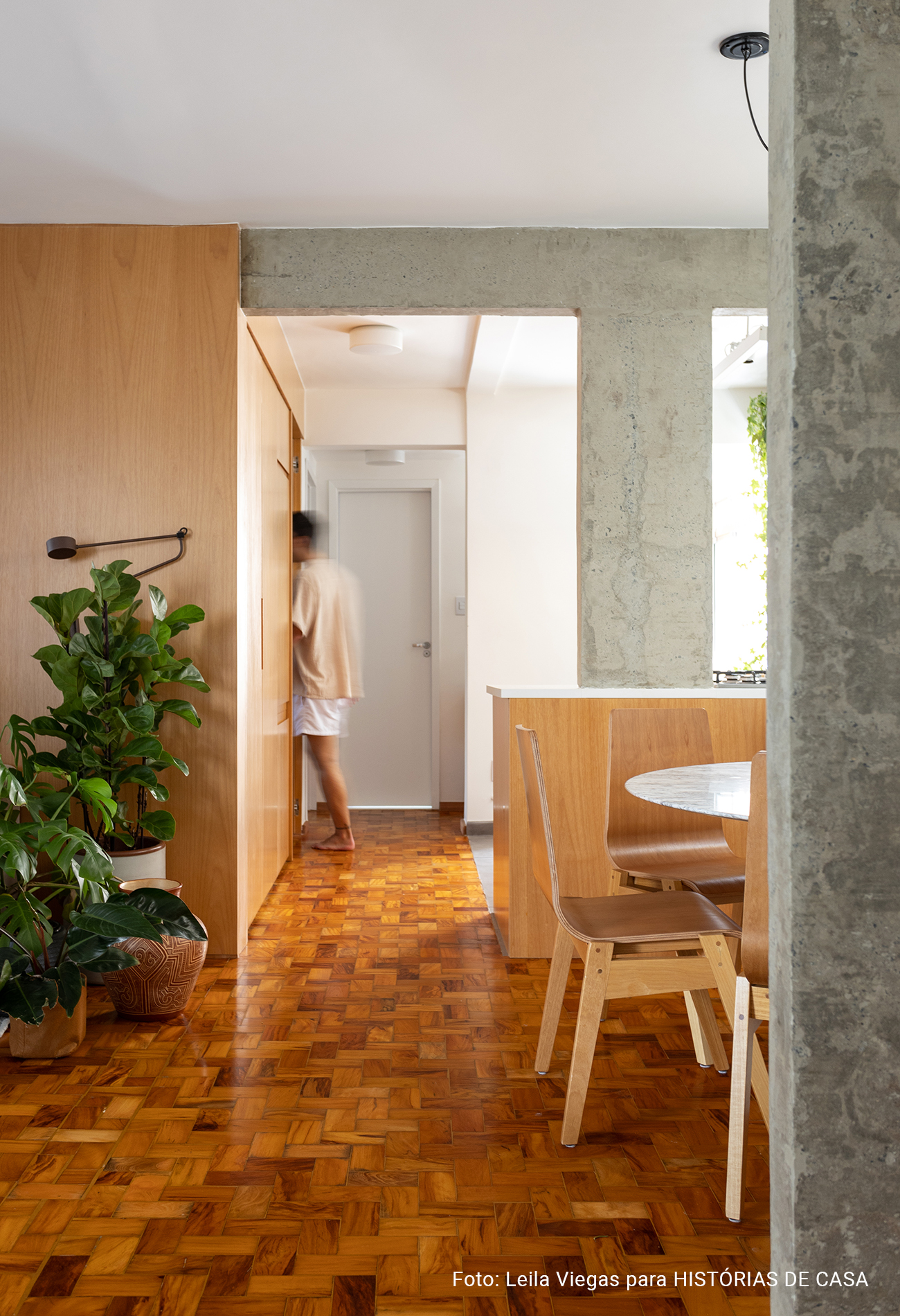 Apartamento com concreto, madeira e cozinha integrada.