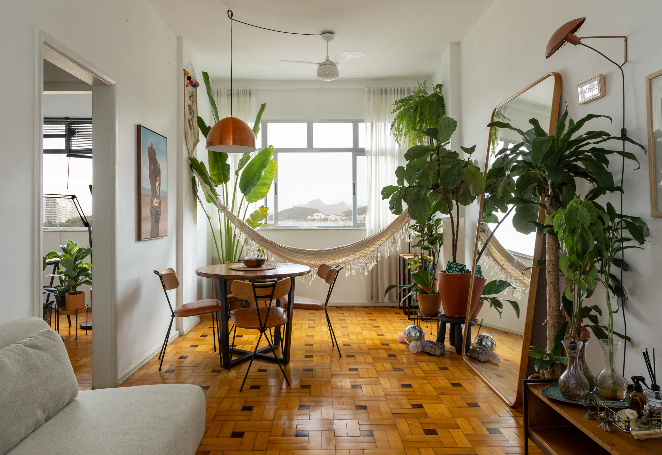 Apartamento com vista para a praia no Rio de Janeiro tem piso de tacos e decoração com plantas.