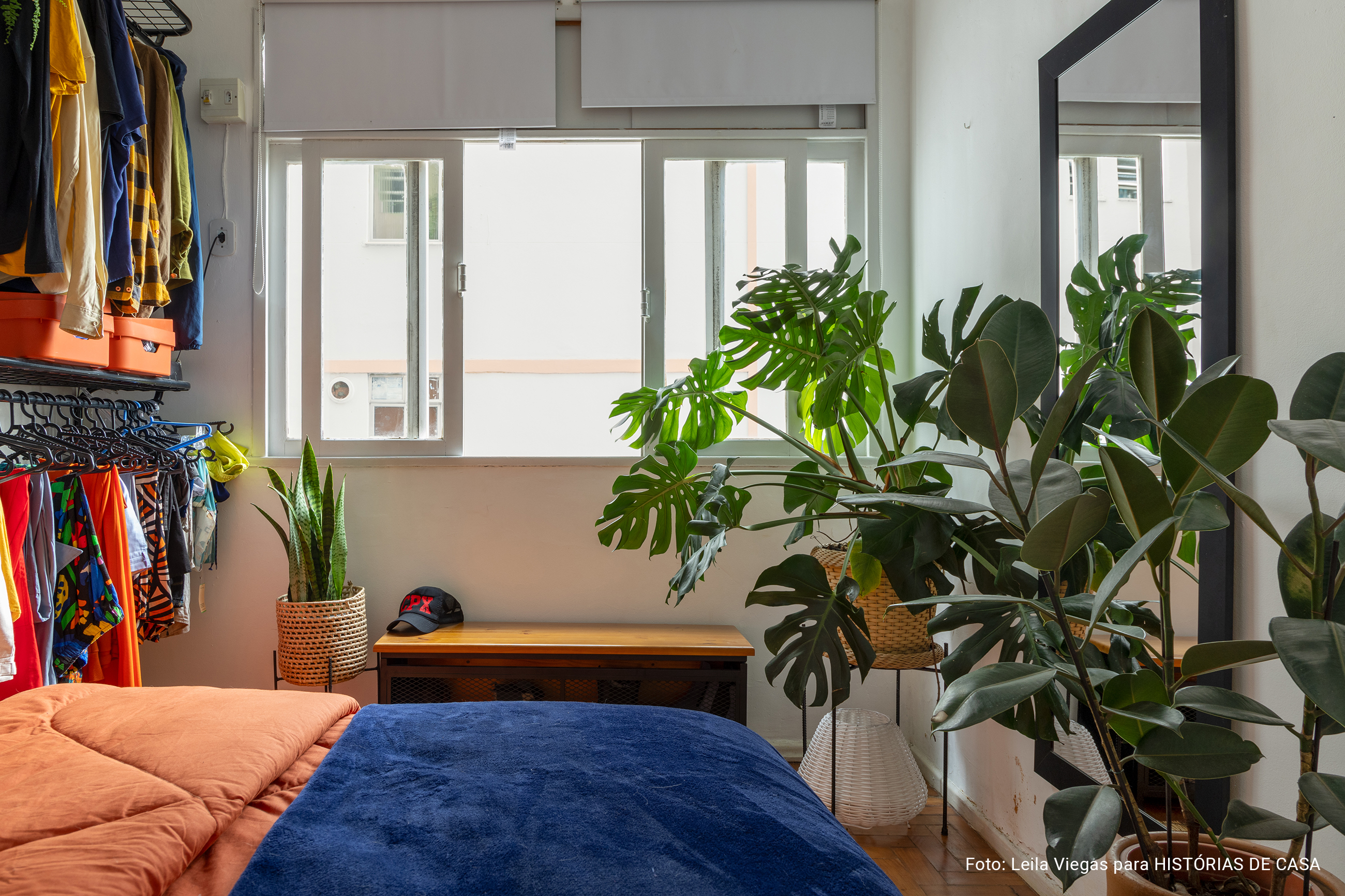 Apartamento pequeno, quarto com plantas e roupa de cama colorida