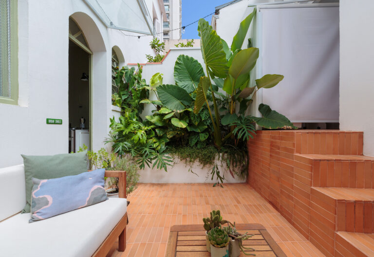 Casa de vila com paredes coloridas, móveis de família e quintal nos fundos.