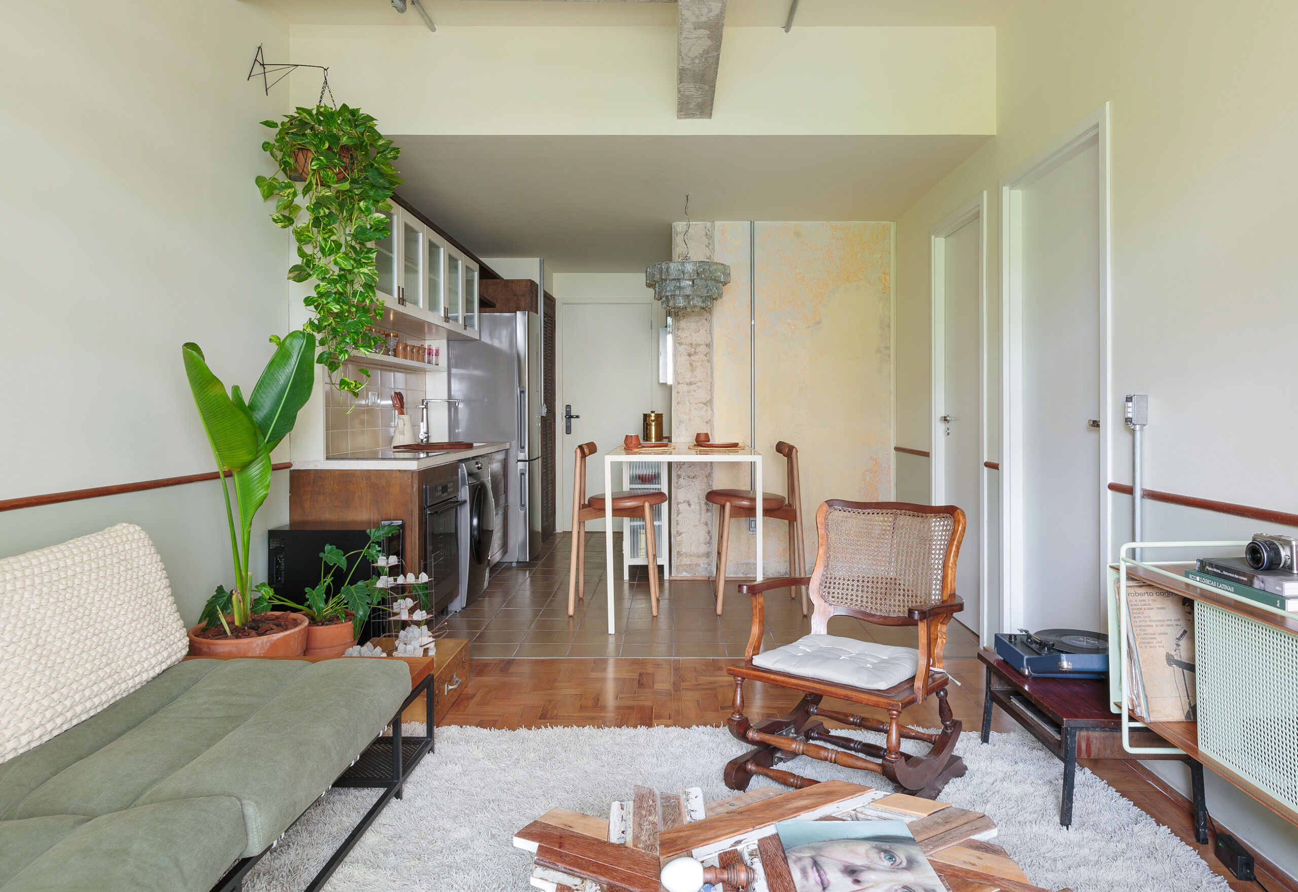 Apartamento conceito no Edifício Vírginia tem cozinha integrada, sacada com plantas, piso de taco e decoração com garimpos.