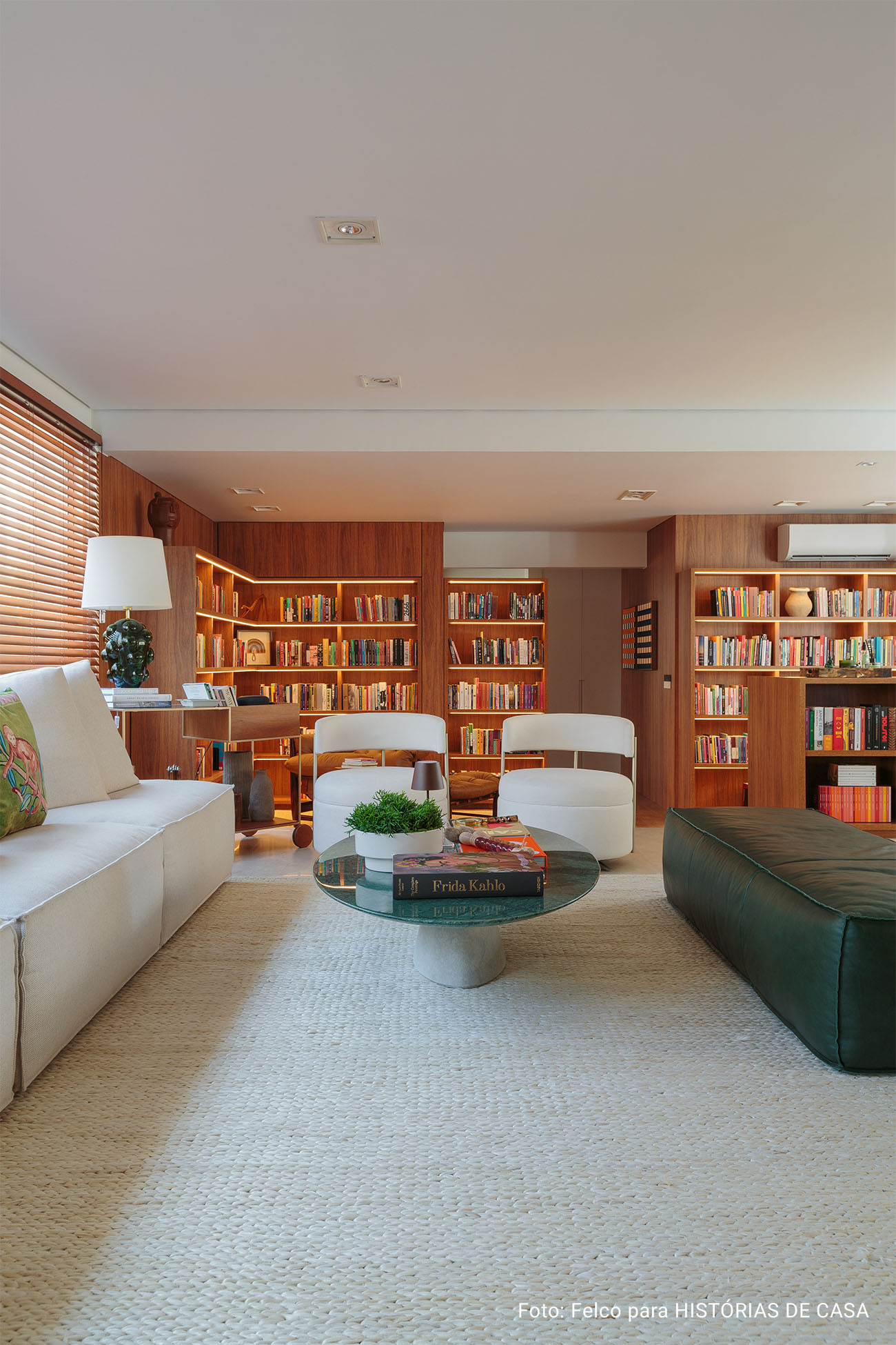 Apartamento integrado com sala aberta e estante de madeira com muitos livros