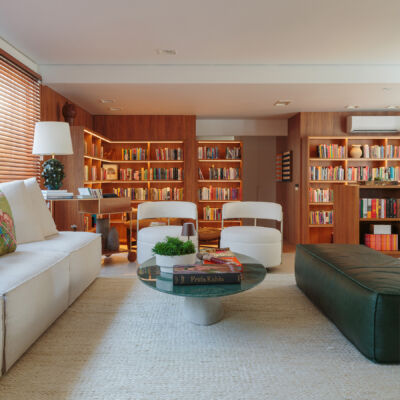 Apartamento integrado com sala aberta e estante de madeira com muitos livros