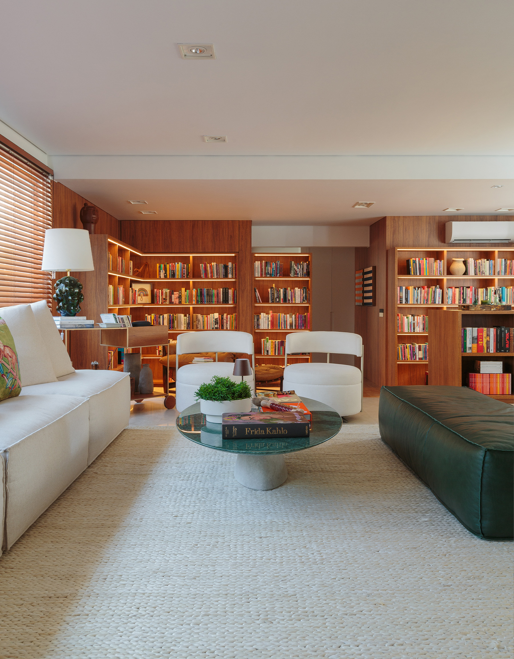 Apartamento integrado com sala aberta e estante de madeira com muitos livros