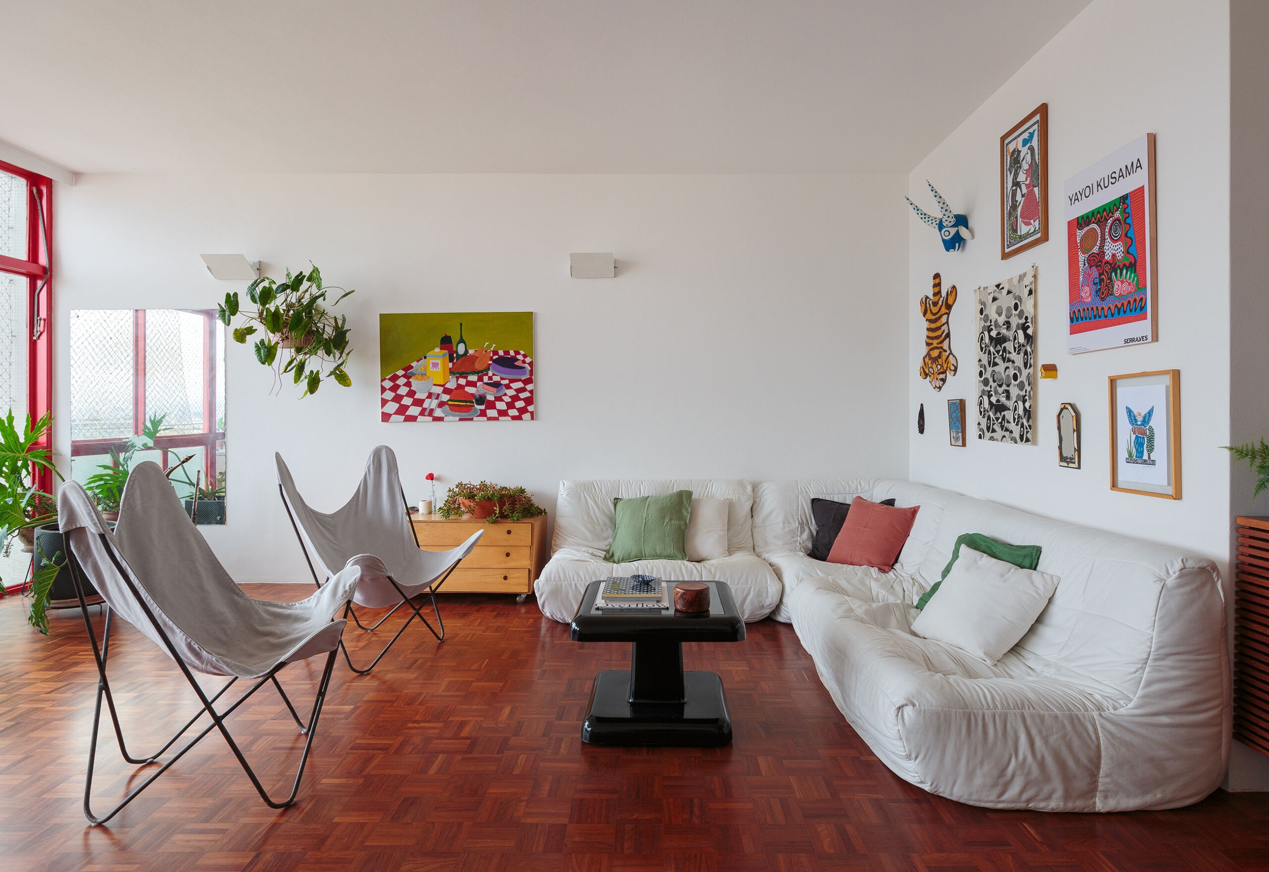 Apartamento com piso de taco, esquadrias vermelhas, sofá branco e cozinha reformada com produtos Celite