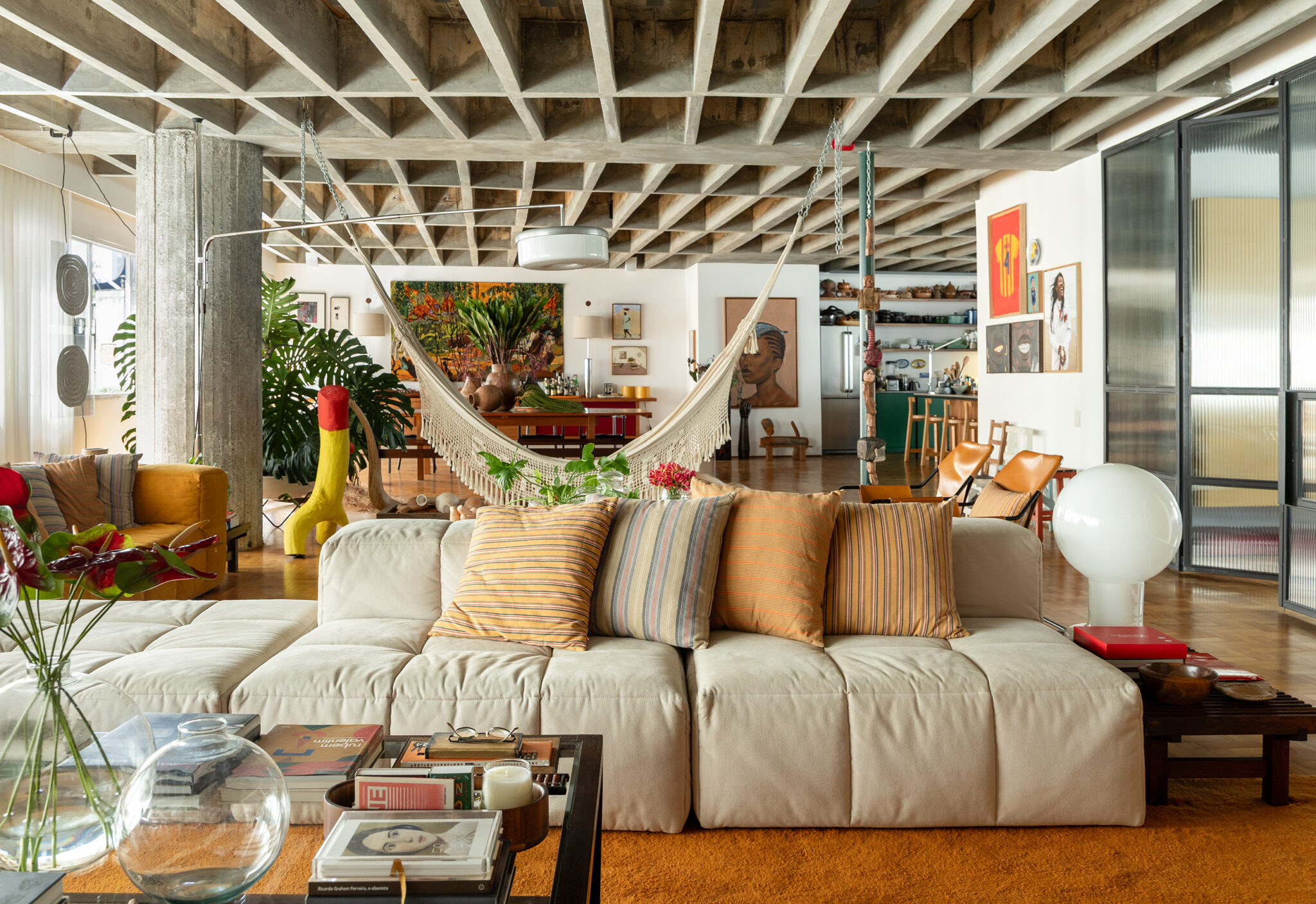 Apartamento de Ademir e André Bueno em Higienópolis, com laje de concreto aparente, ambientes integrados e obras de arte